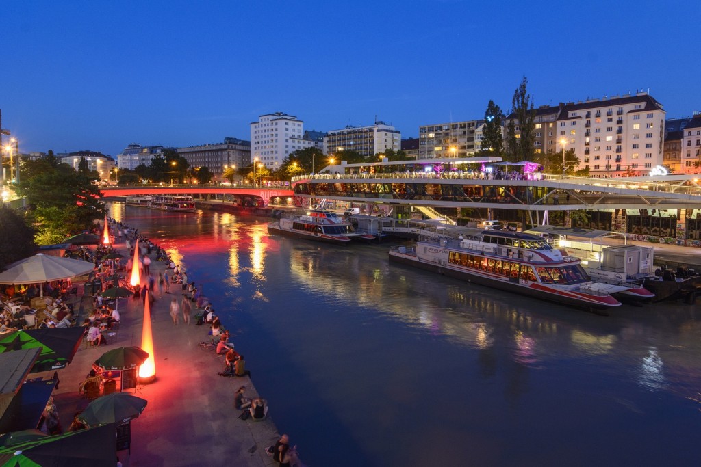 Donaukanal (Danube Canal) boat station Wien City , excursion boats, ship - restaurant "Motto am Fluss" Shore restaurants, people sitting on seawall